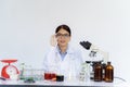 Female scientist holding her glasses and looking with both test tubes and writes experimental summary on clipboard while Royalty Free Stock Photo