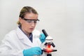 Woman with a microscope. Serious female chemist is working in a laboratory. Scientist researcher using microscope in laboratory.