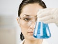 Female scientist looking at beaker of liquid