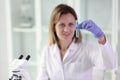 Female scientist looks at test tube with liquid in her hand.