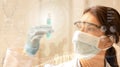 Female scientist with mask and laboratory glasses analyzes a test tube on digital background with dna and holographic images