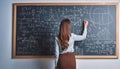 Female Scientist Solving Complex Equations on Chalkboard: Advanced Mathematics and Physics