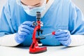 Female scientist studying cotton swab sample specimen under microscope Royalty Free Stock Photo