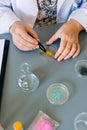 Female scientist with tweezers analyzing golden glitter sample over petri dish on research lab