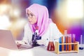 Female scientist using laptop and microscope