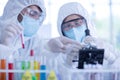 A female scientist wearing a mask and looking through the microscope in the laboratory Royalty Free Stock Photo