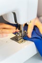 Female seamstress sewing or stitching fabric with professional machine