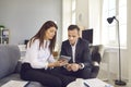 Female secretary with digital tablet in hands shows electronic documents to her boss.