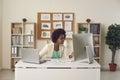 Female secretary working simultaneously on computer and laptop sitting at her workplace.