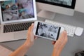 Female security guard monitoring home cameras using smartphone indoors Royalty Free Stock Photo