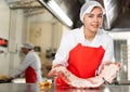 Female seller demonstrating meat in butcher shop