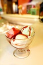 Female Seller pours sauce on ice cream. Woman hard making ice cream copper cup with forest fruit and candy.