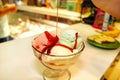 Female Seller pours sauce on ice cream. Woman hard making ice cream copper cup with forest fruit and candy.