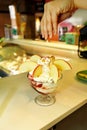 Female Seller pours sauce on ice cream. Woman hard making ice cream copper cup with forest fruit and candy.