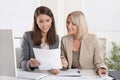 Female senior and junior managers sitting at desk working together in a business team. Royalty Free Stock Photo