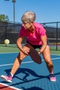 Female senior female player readies her paddle to volley the pickleball