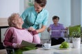 Senior residents in living room of nursing facility with supporting nurse