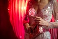 female in sequined dress, sparkly lollipop, holding purse