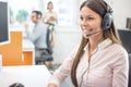 Female service desk consultant talking on hands-free phone in call center. Royalty Free Stock Photo