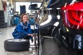 Female service mechanic changing the front tire of a car Royalty Free Stock Photo