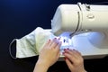 A female sewing a homemade face mask on a black table Royalty Free Stock Photo
