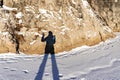 Female shadow with long legs and a raised hand on fresh snow and a rock on a winter sunny day. Abstract