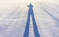 Female shadow with long legs and a raised hand on fresh snow on a winter sunny day. Abstract