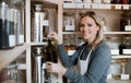 A female shop assistant in a zero waste shop, filling a bottle with olive oil.