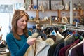 Female Shopper In Thrift Store Looking At Clothes