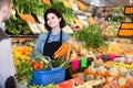 Female shopping assistant helping customer to buy fruit and vegetables in grocery shop Royalty Free Stock Photo