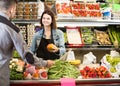 Female shopping assistant helping customer to buy fruit and vegetables in grocery shop Royalty Free Stock Photo