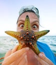 Female showing a green starfish and doing an amazed surprised eyes. Exotic vacation concept image