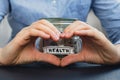 Female showing heart with hands sign Saving Money In Glass Jar filled with Dollars banknotes. HEALTH transcription in Royalty Free Stock Photo