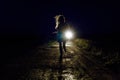 female silhouette on a night country road running away from pursuers by car in the light of headlights