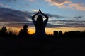 Female silhouette in a pose for meditation in a sunset.