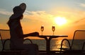 Female silhouette on sunset behind table