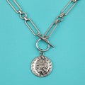 Female silver lion head pendant with chain on bright blue textured background