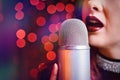 Woman singer with disco mic on bokeh light background. Royalty Free Stock Photo