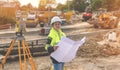 Female site engineer surveyor working with theodolite total station EDM equipment on a building construction site outdoors toned Royalty Free Stock Photo