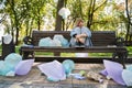 Female sitting at bench embracing her legs and being afraid of great amount of rubbish