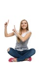 Female sitting with crossed legs on the floor pointing up Royalty Free Stock Photo