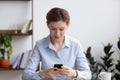 Female sitting in office room holding smartphone reading message Royalty Free Stock Photo