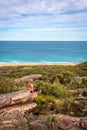 Female sitting on rocks in active wear with views out to beach and ocean