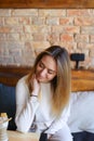 Female sitting on wooden chair near table with cup of coffee and posing for photo. Royalty Free Stock Photo