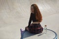 Young inline roller blader female posing in a skate pool. Portrait of a skater person sitting on a ramp top with a glass bottle of