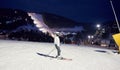 Female skier after skiing day standing on skis. Ski resort lighted by lanterns and mountain in darkness on background. Royalty Free Stock Photo