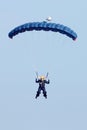 Female sky diver with bright blue open parachute