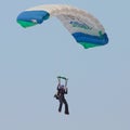 Female sky diver with brightly coloured open parachute gliding i