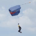 Female sky diver with brightly coloured open parachute landing a