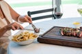 Female slicing a steak at a dinner table, with a plate of fries and wine beside them Royalty Free Stock Photo